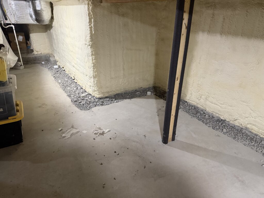 B‑Dry interior drainage pipe installed in clean stone below the basement floor