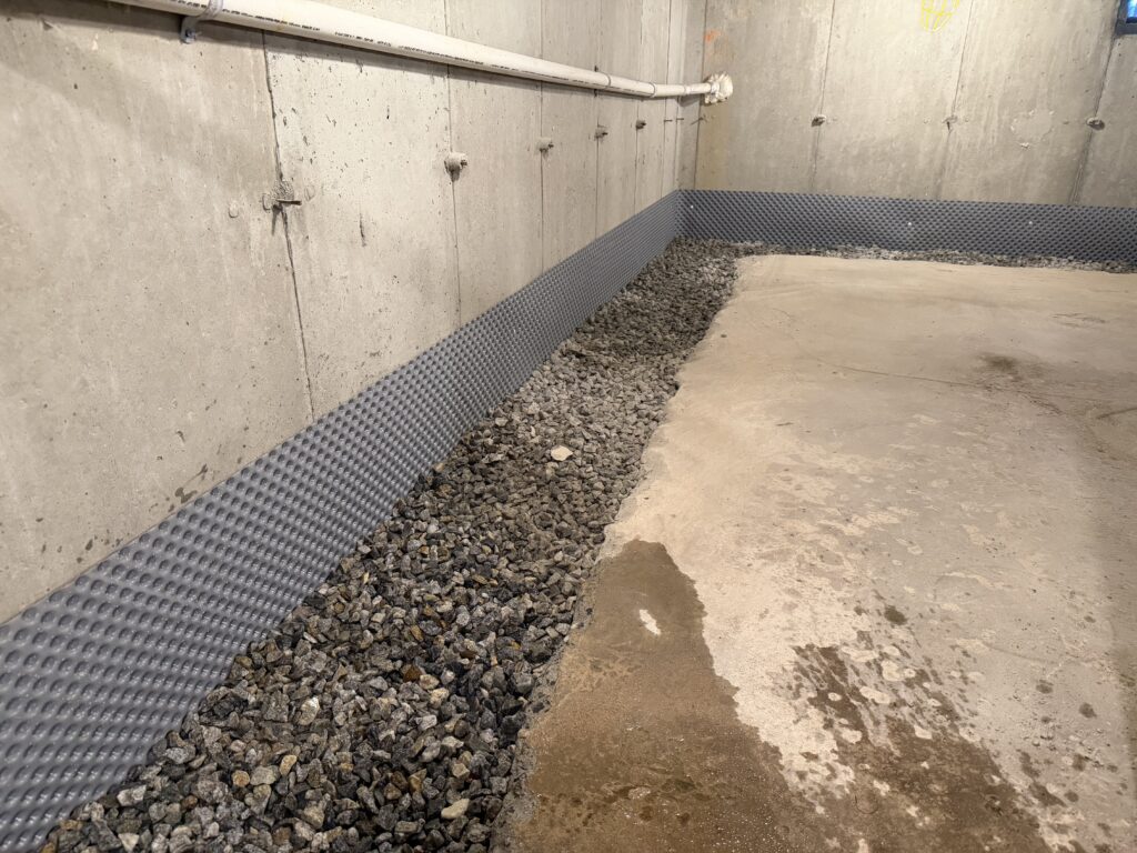 B‑Dry drainage pipe, clean stone and wall membrane prepared for concrete replacement