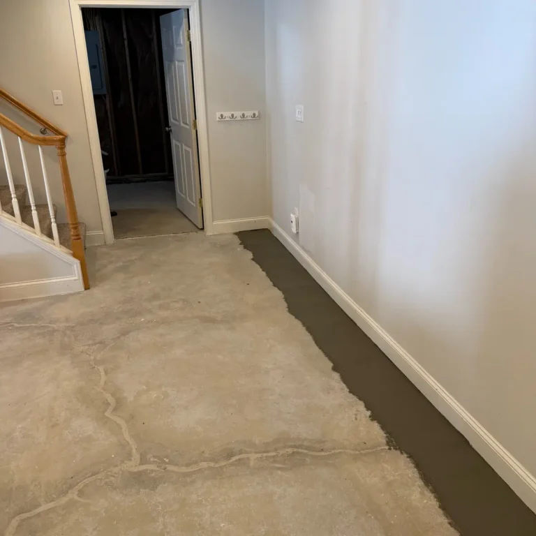 Finished basement with fresh concrete covering the installed B‑Dry interior French drain